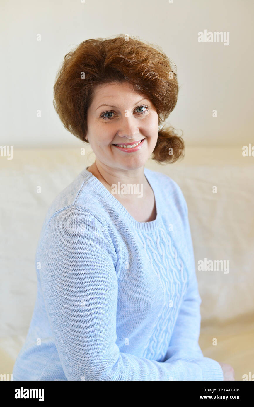 woman in a blue sweater sitting on sofa Stock Photo - Alamy