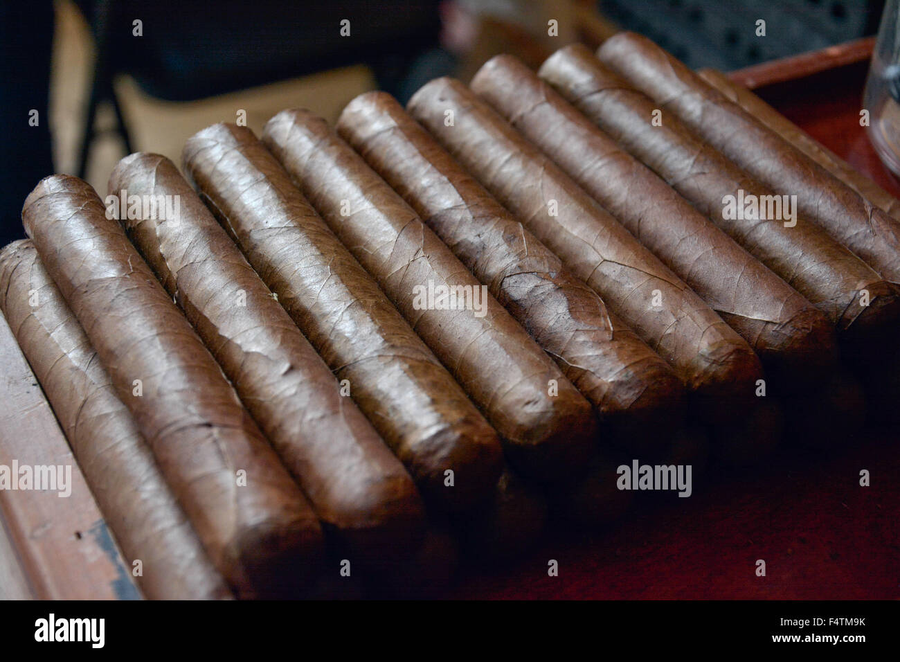 Moody, artistic and nostalgic view of Hand rolled Cuban cigars stacked in cigar factory work bench area Stock Photo