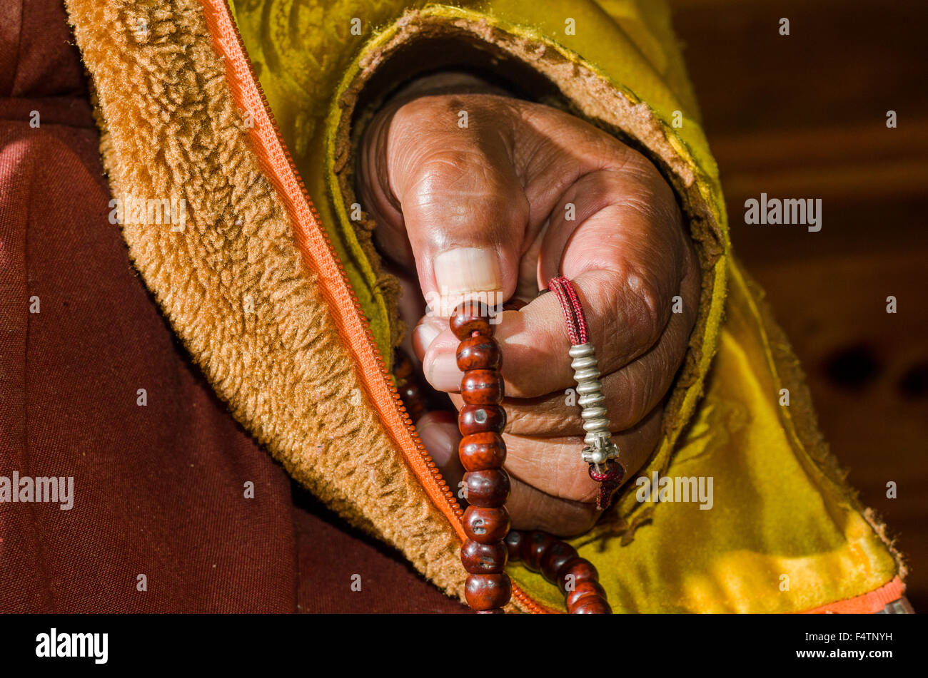 Hand of a monk praying and counting beads at a mala Stock Photo