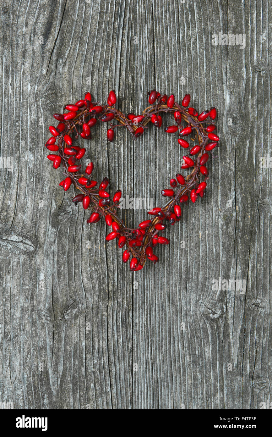 heart-shaped rose hips berry wreath in wooden door Stock Photo
