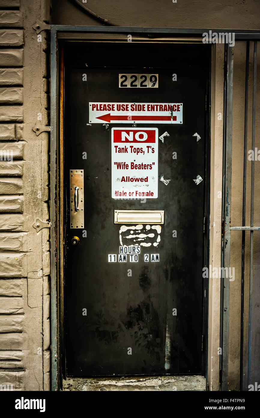 Dress code posted on funky beat-up door of dive bar, 'No tank tops, T's or wife beaters allowed Male or Female' Stock Photo