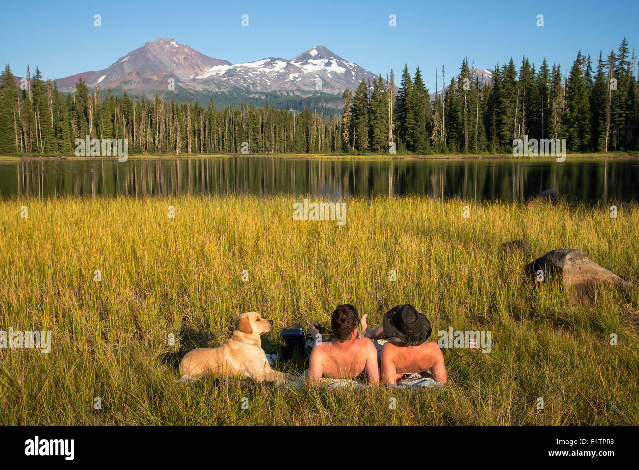 USA, Oregon, Lane County, Willamette, National Forest, Scott Lake, couple with dog tanning at lake    MR 0514, 0515 Stock Photo