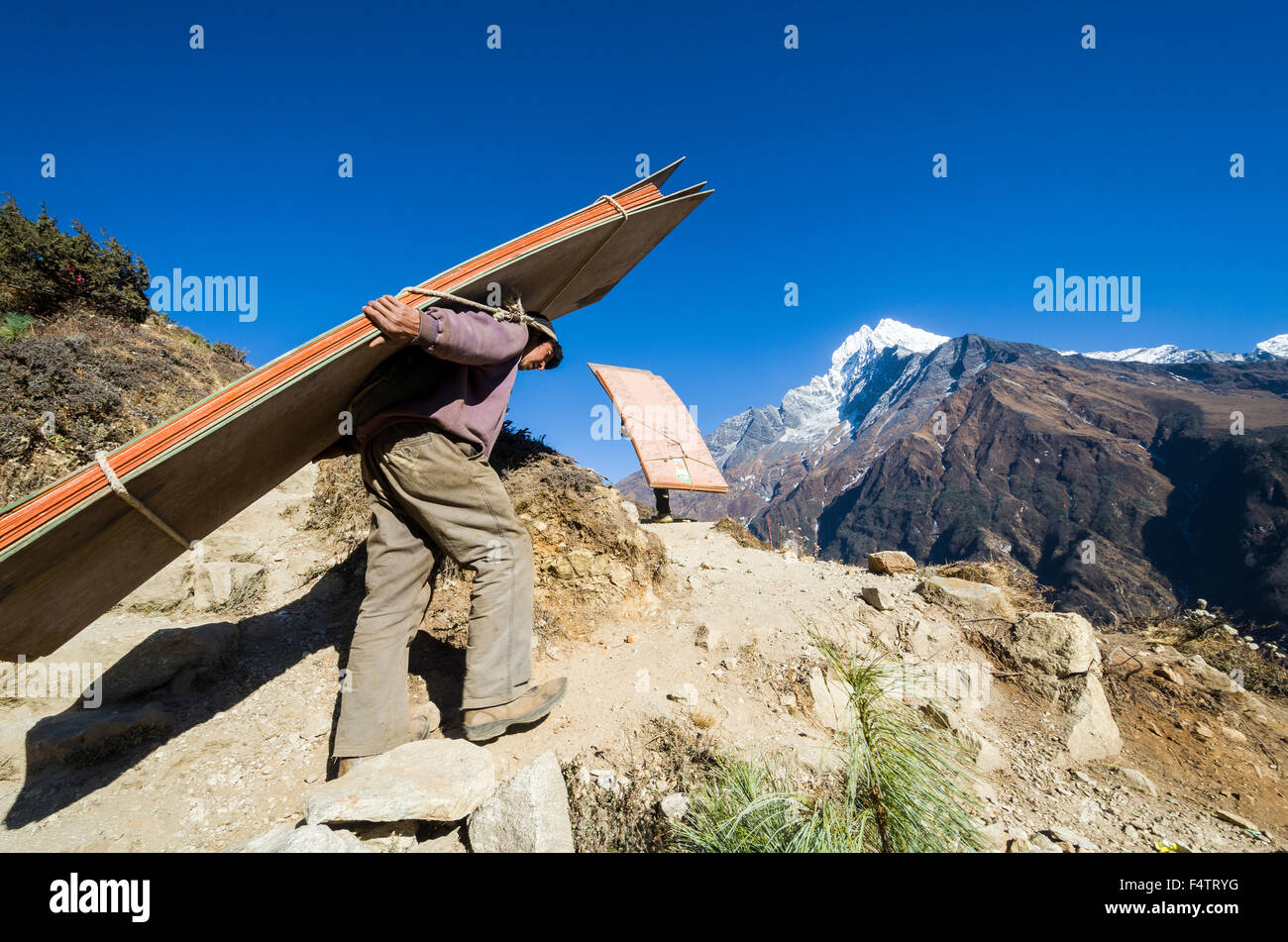 Porter carrying heavy load up an ascending track above Namche Bazar (3. ...