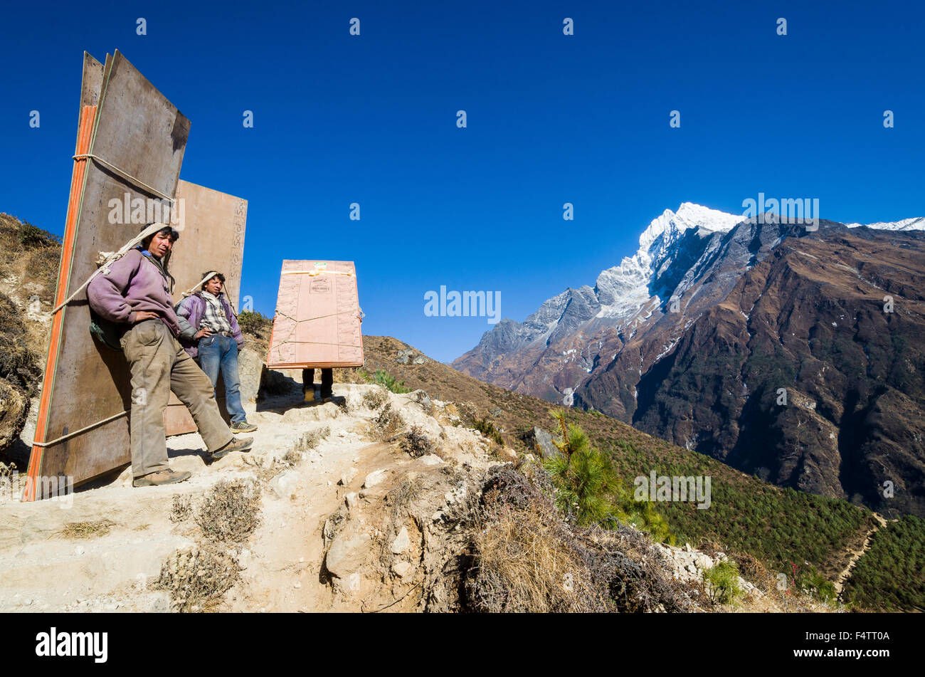 Porters carrying heavy load up an ascending track above Namche Bazar (3 ...