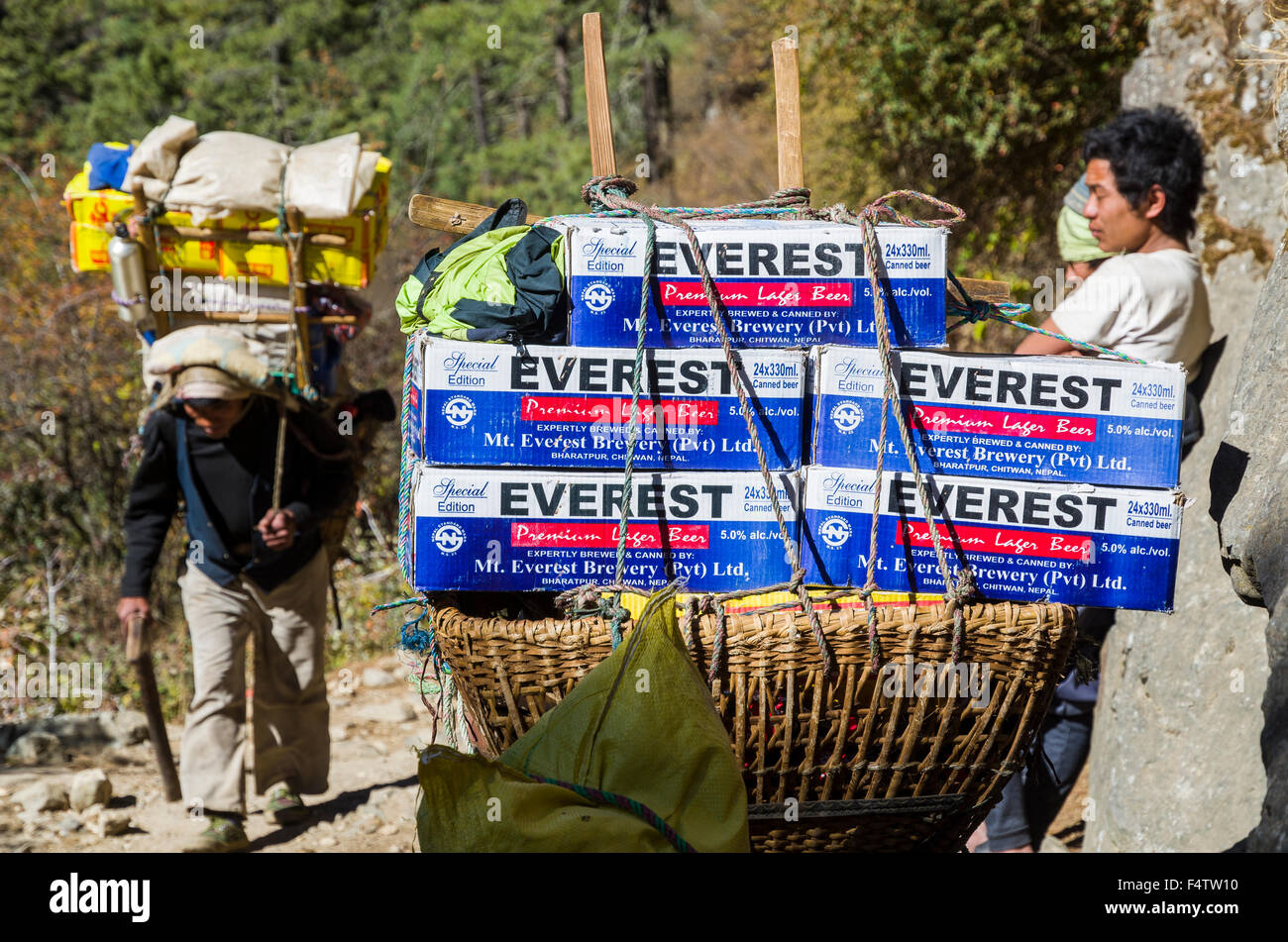 Porters carrying heavy load up an ascending track above Namche Bazar (3 ...