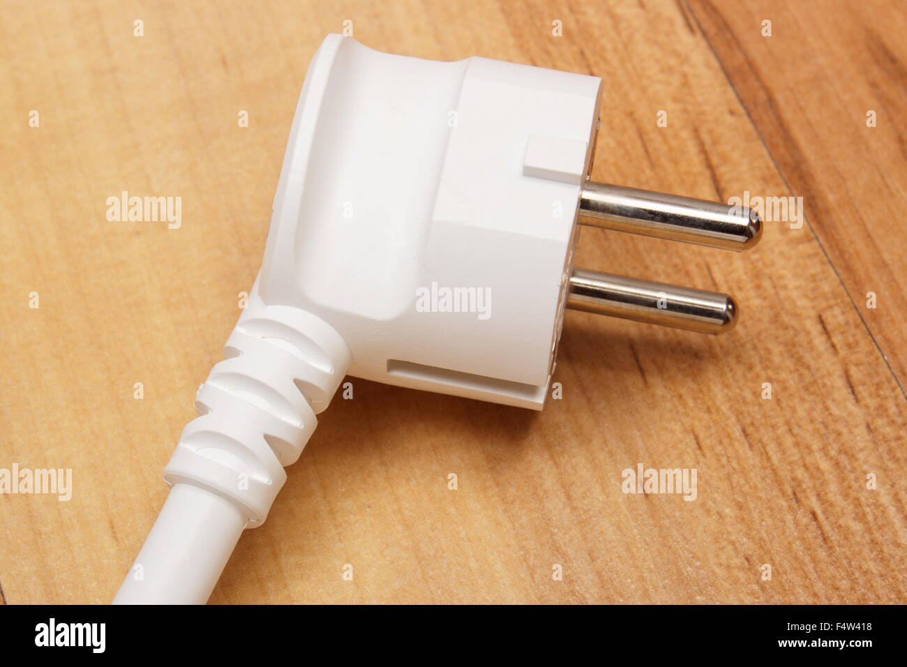 Electrical white plug lying on wooden floor, technology Stock Photo - Alamy