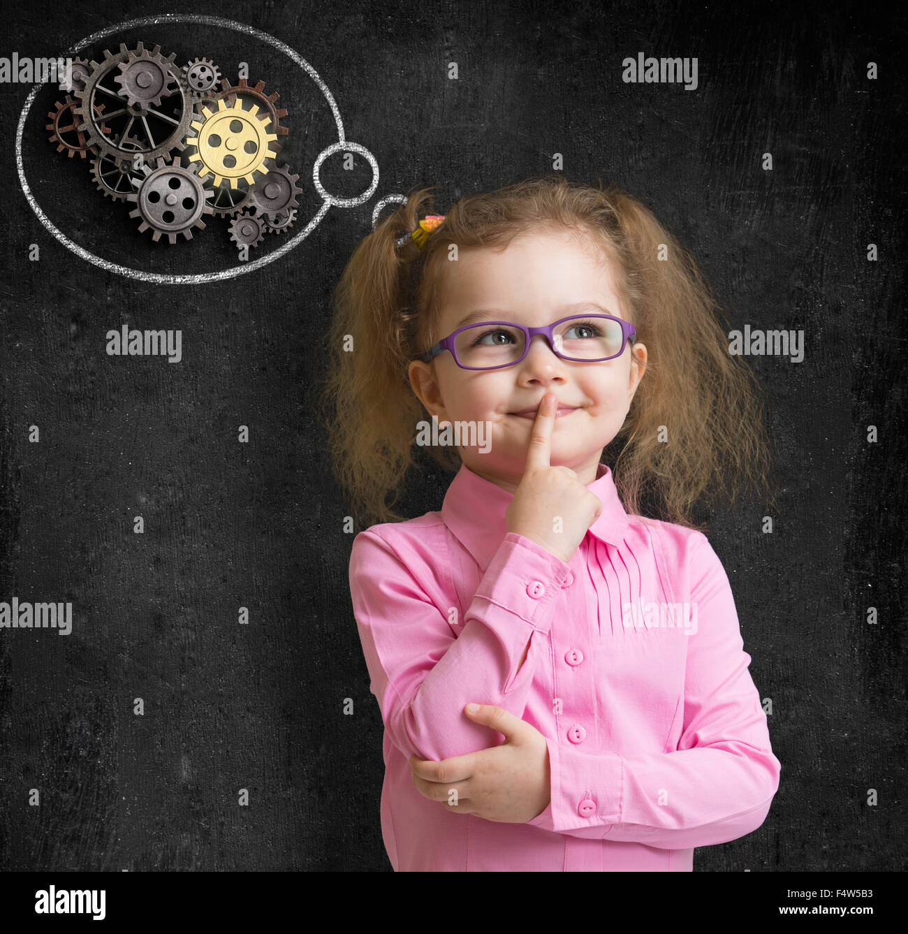 kid girl in glasses with bright idea standing near school blackboard Stock Photo