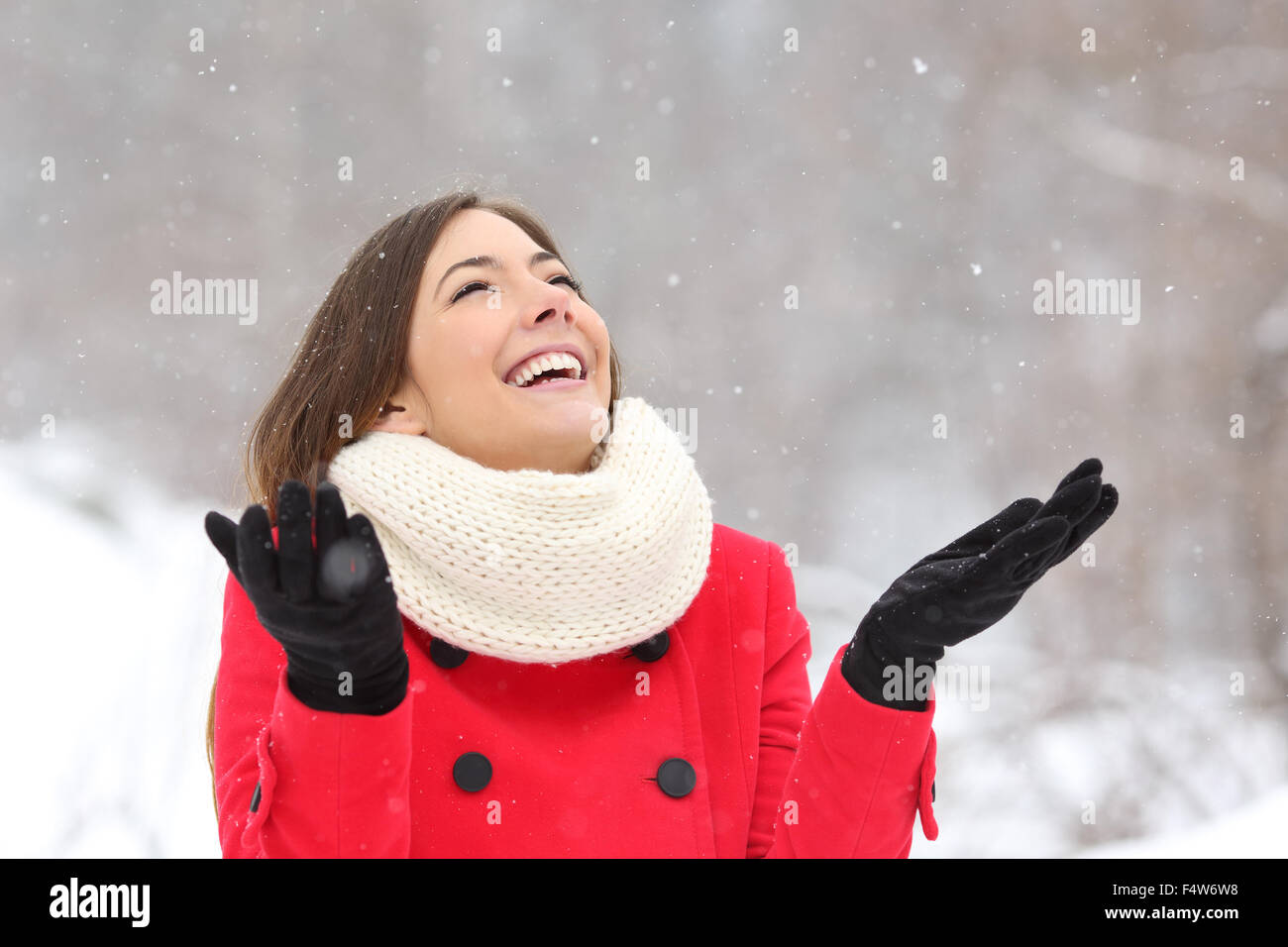 Candid happy girl enjoying snow in winter wearing a red jacket Stock Photo