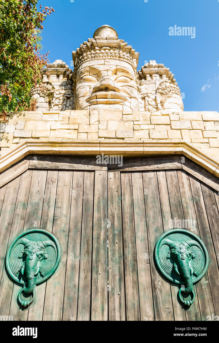 Stone faces of a temple and wooden portal with door knocker shaped like elephant's head. Stock Photo