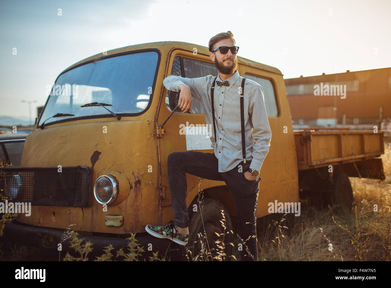 Portrait of a young handsome stylish man, wearing shirt and bow-tie with old cars Stock Photo