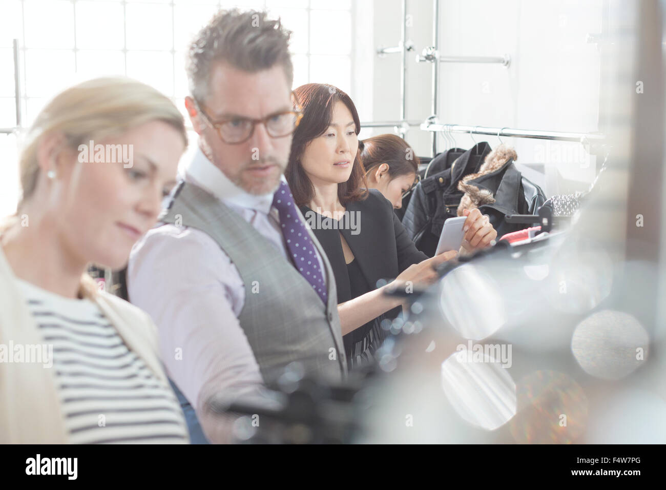 Fashion designers reviewing clothing on racks Stock Photo