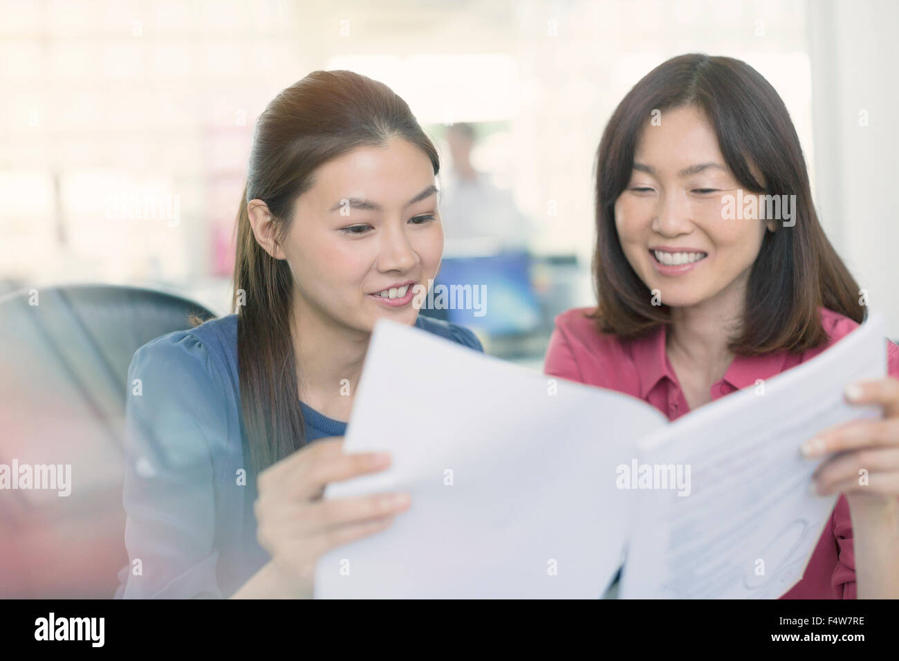 Smiling businesswomen discussing paperwork in office Stock Photo - Alamy