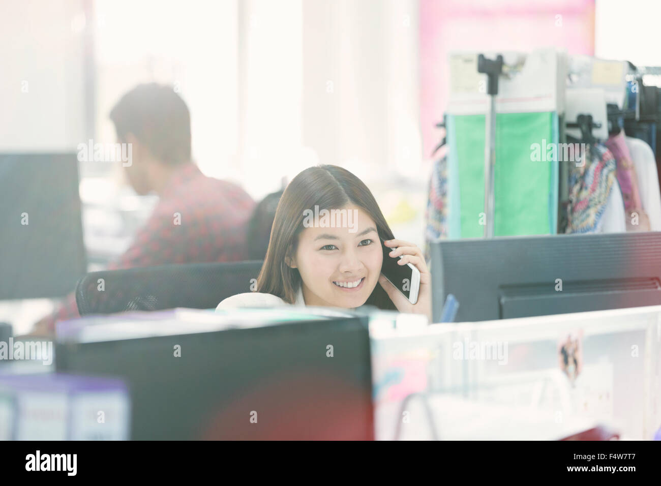 Smiling fashion designer talking on cell phone at desk in office Stock Photo