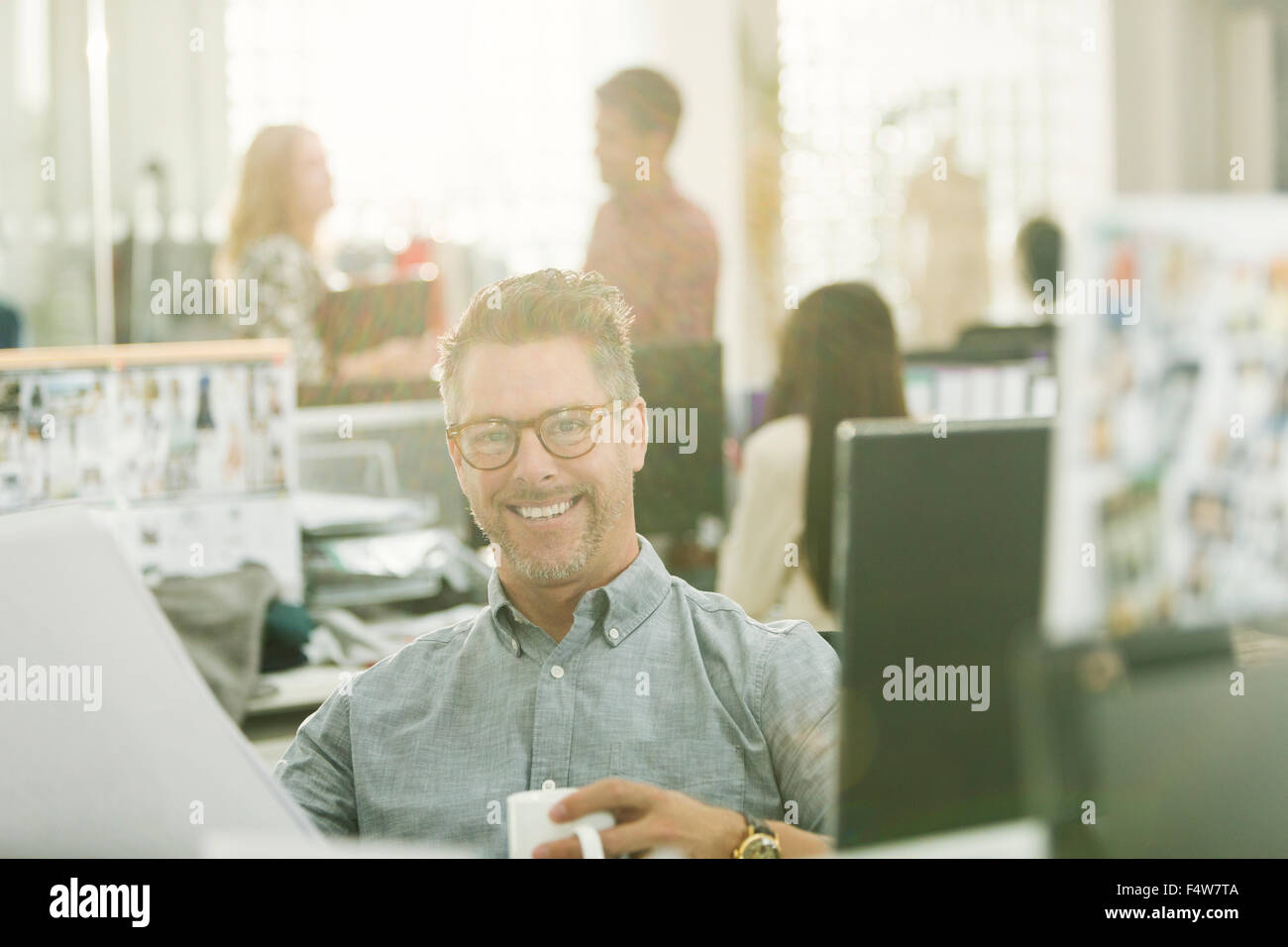 Portrait smiling fashion designer drinking coffee in office Stock Photo
