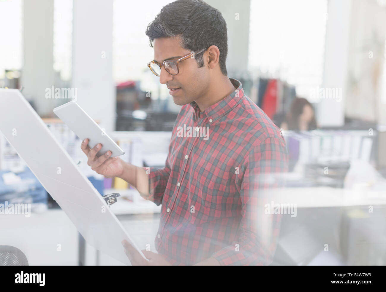 Fashion designer with digital tablet examining story board in office Stock Photo