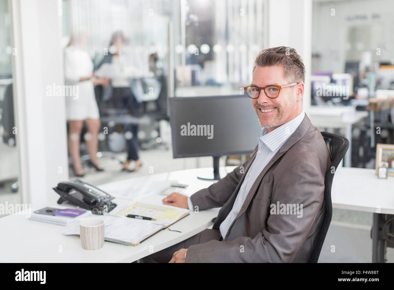 Portrait confident businessman at desk in office Stock Photo