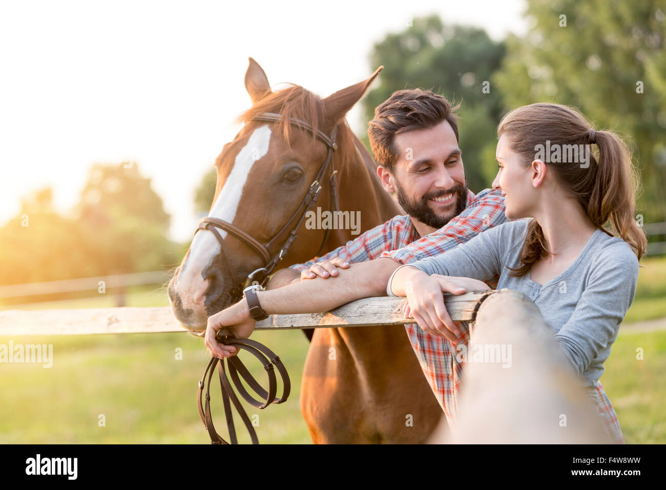 Couple with horse talking at rural pasture fence Stock Photo
