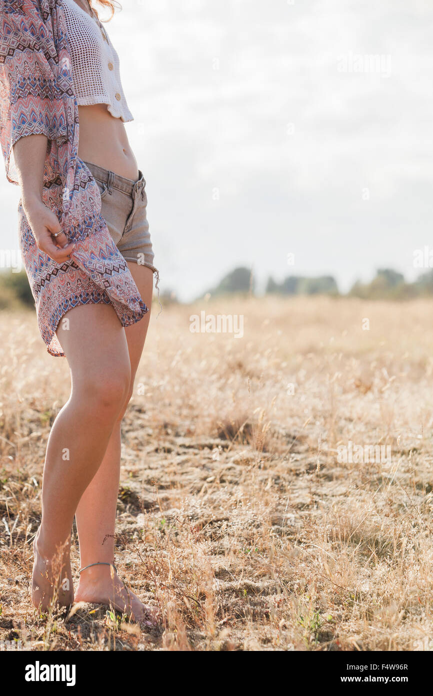 Boho woman standing in sunny rural field Stock Photo