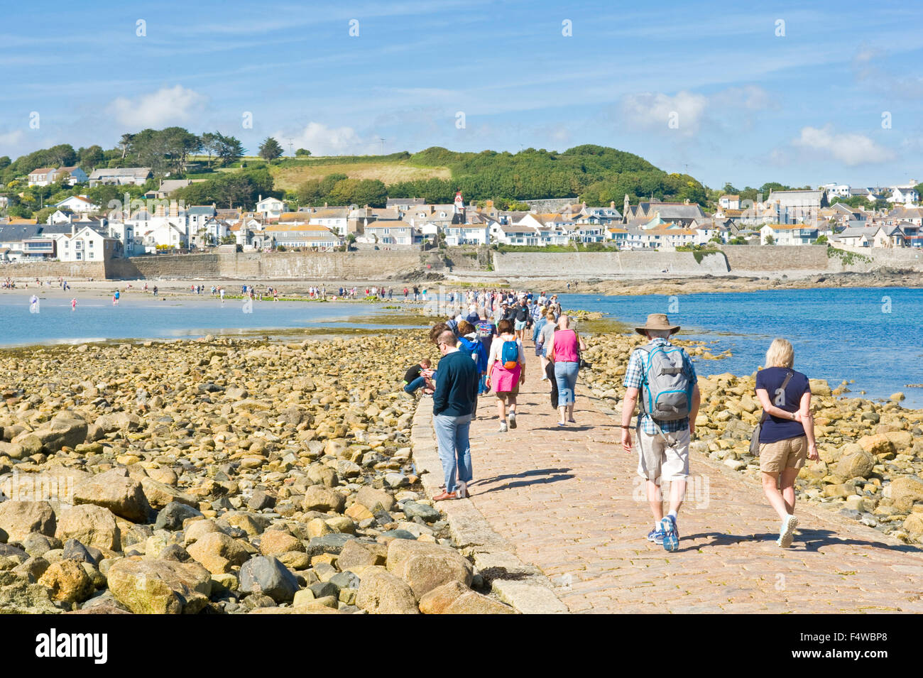 A view of people walking to and from St Michael's Mount along the causeway with the town of Marazion in the background. Stock Photo