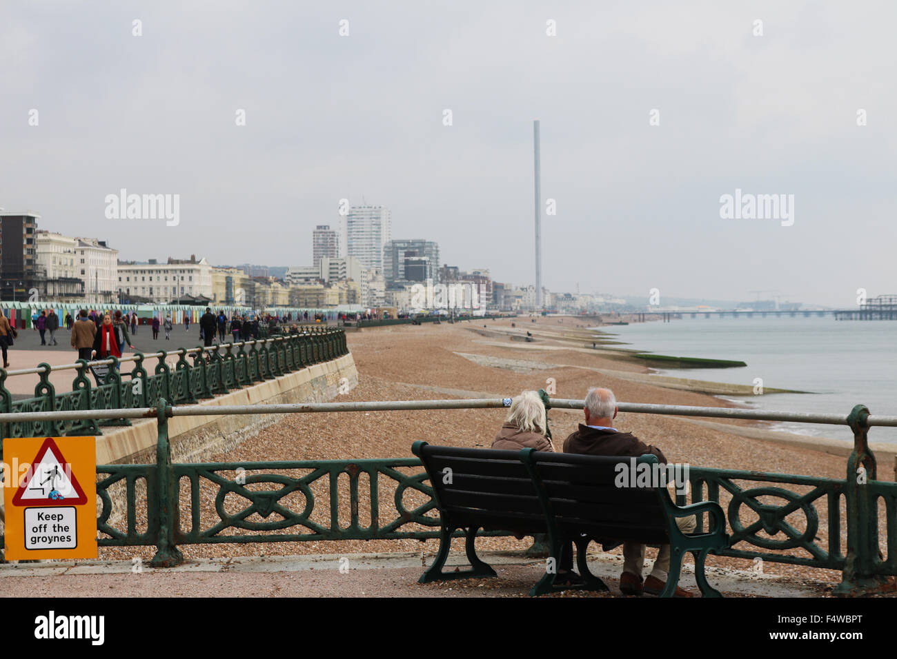 Couple sitting on a bench looking out at Brighton City skyline by the sea Stock Photo