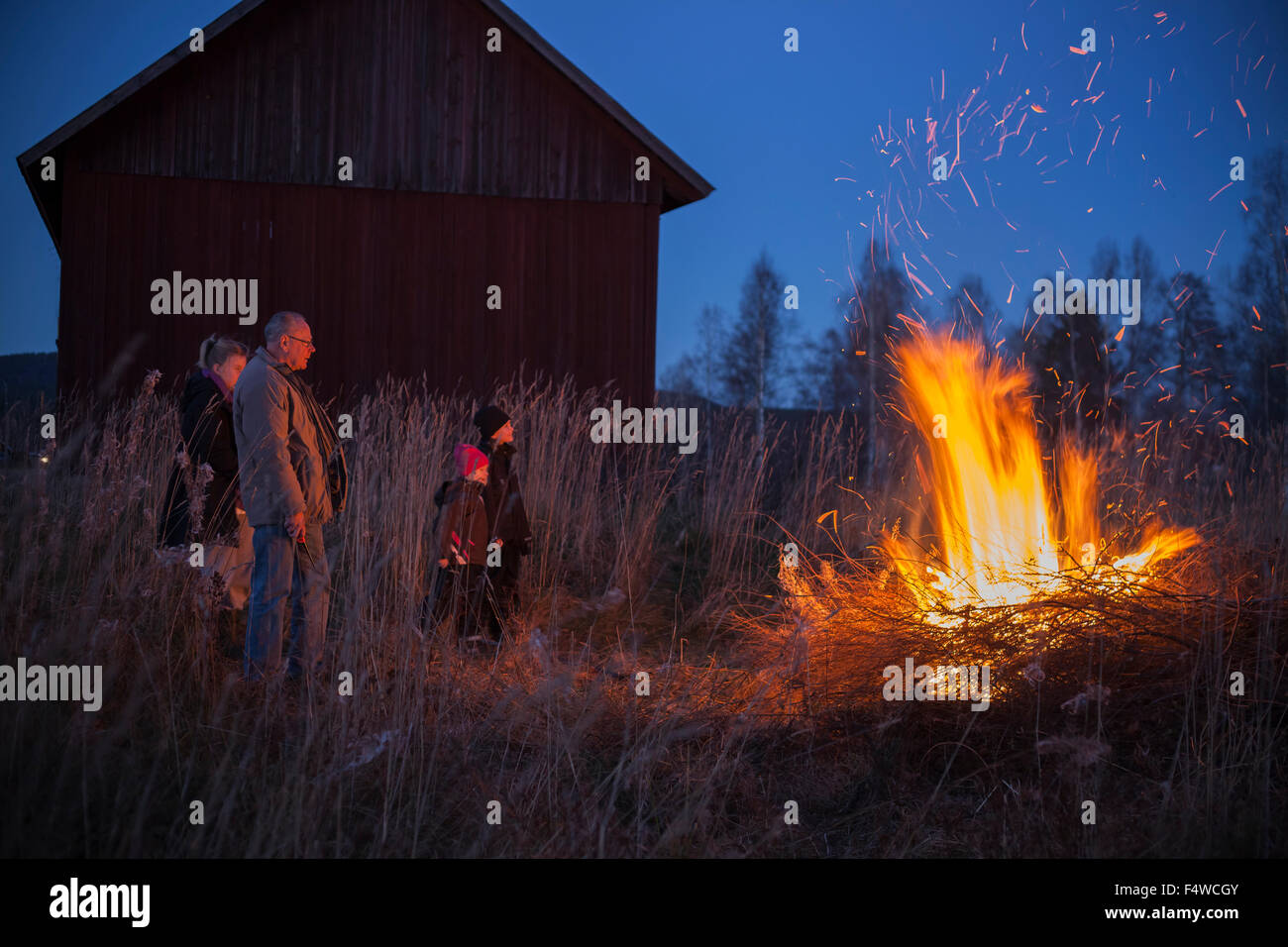 Sweden, Narke, Filipshyttan, Grandfather with grandchildren (6-7,8-9,16-17) looking at bonfire Stock Photo