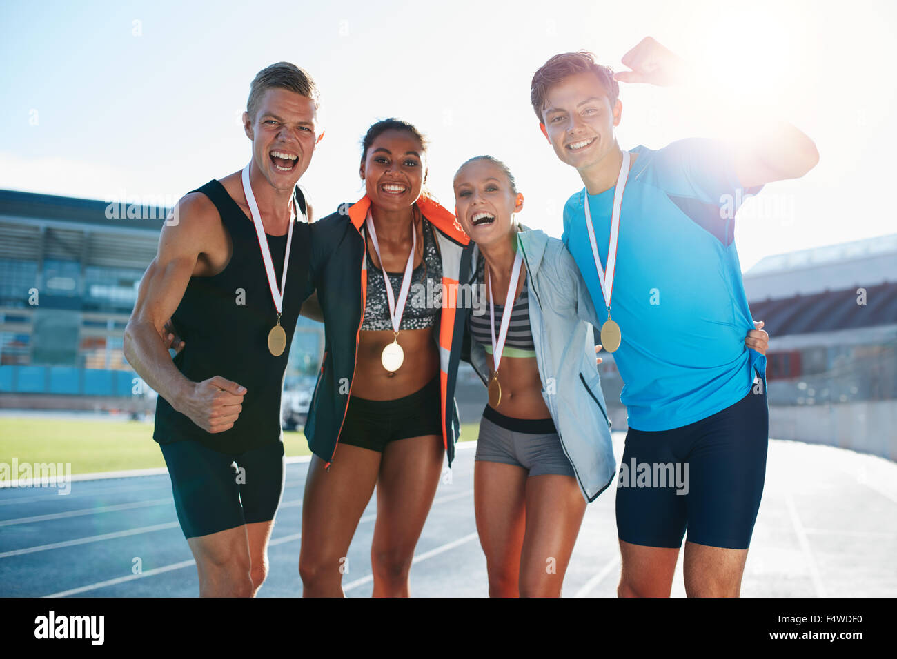 Portrait of young team of athletes enjoying victory. Diverse group of runners with medals