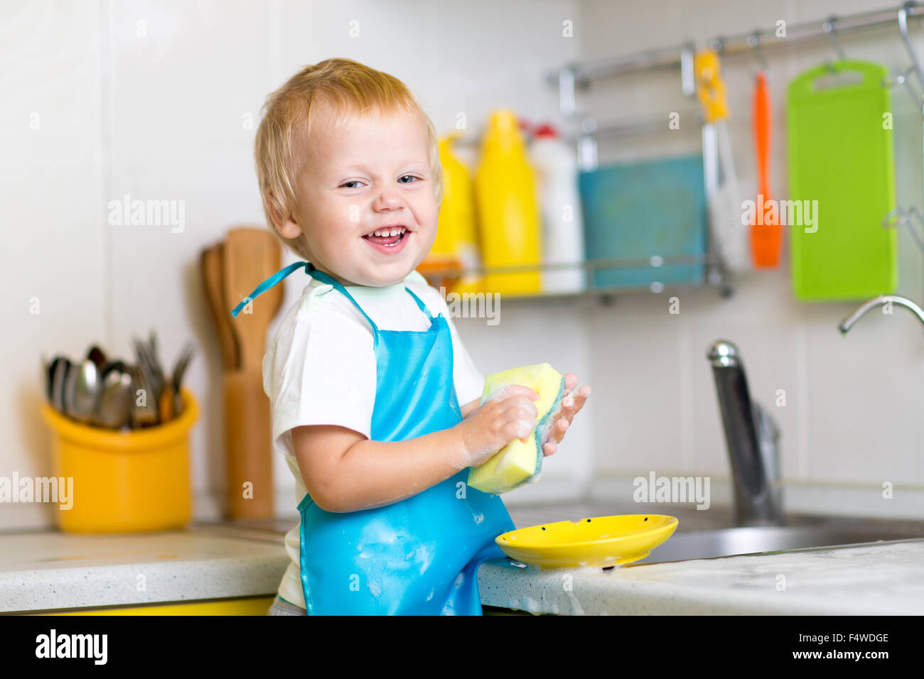 child boy washing dishes in kitchen Stock Photo