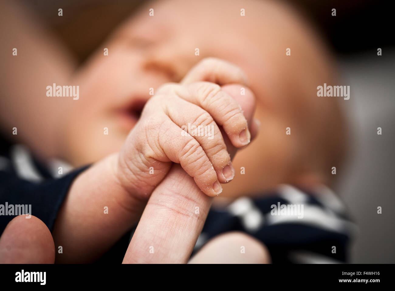 Boy (0-1 months) holding father's finger Stock Photo