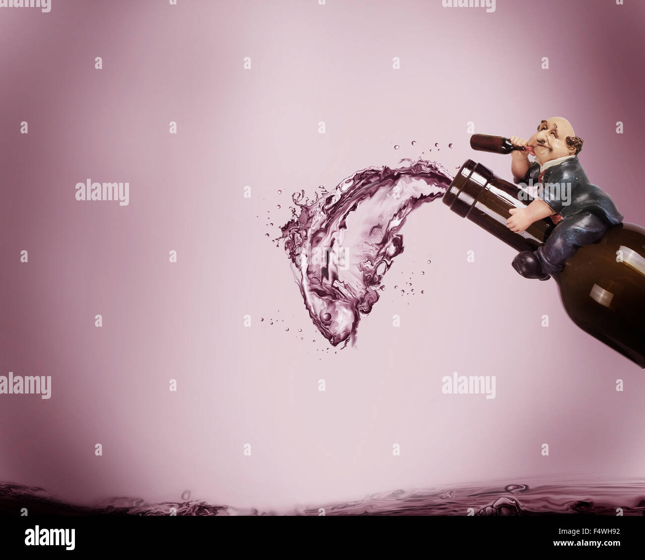 A drunk man sitting of a wine bottle imagining an illusion of a fish made of wine spilling out of the bottle. Stock Photo