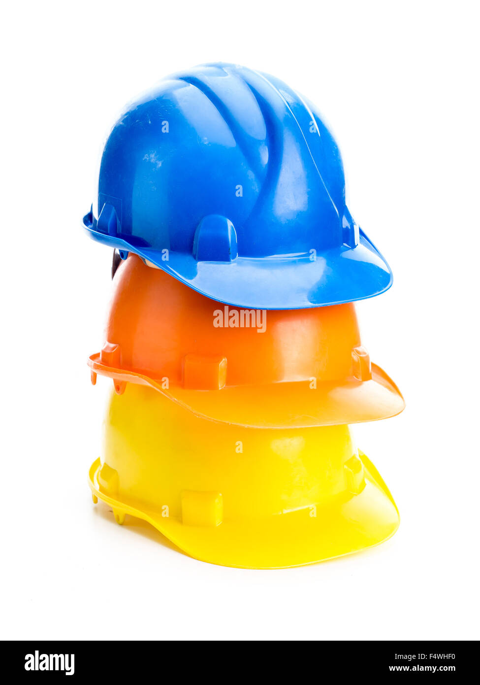 Three hard hats in blue, orange and yellow colors piled up shot on white background Stock Photo