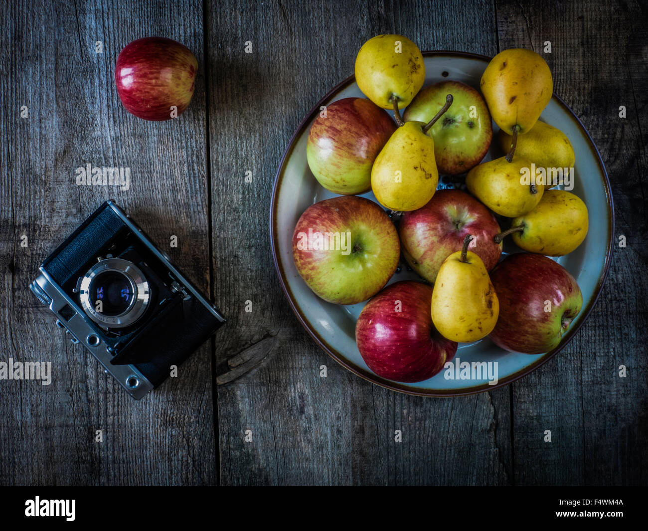 antique photo camera, pears and apples on wooden weathering background Stock Photo