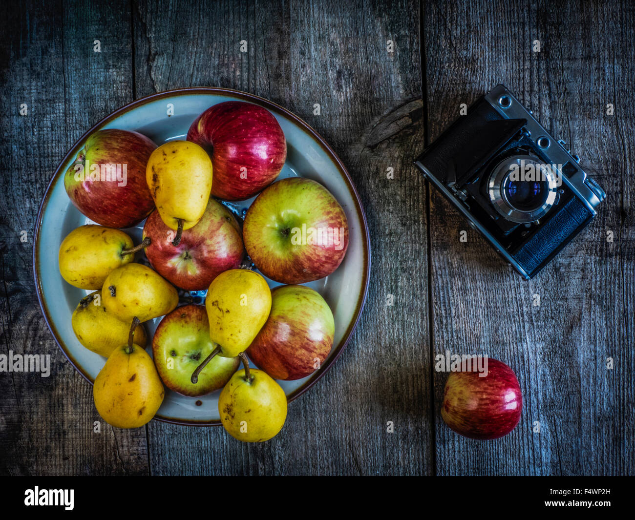 antique photo camera, pears and apples on wooden weathering background Stock Photo