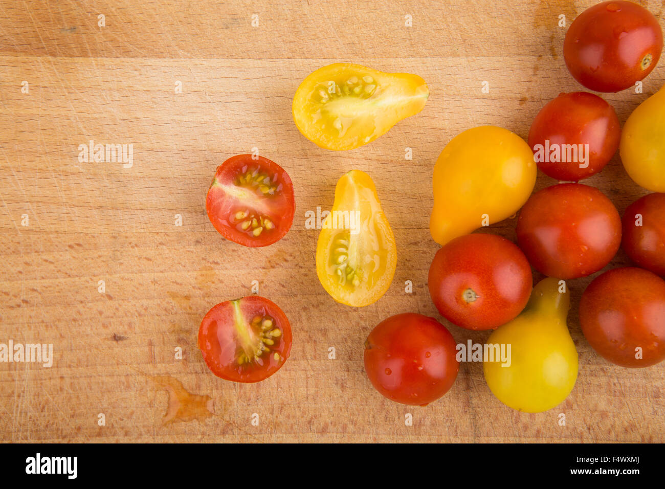 Red and yellow cherry tomatoes on a wooden cutting board Stock Photo ...