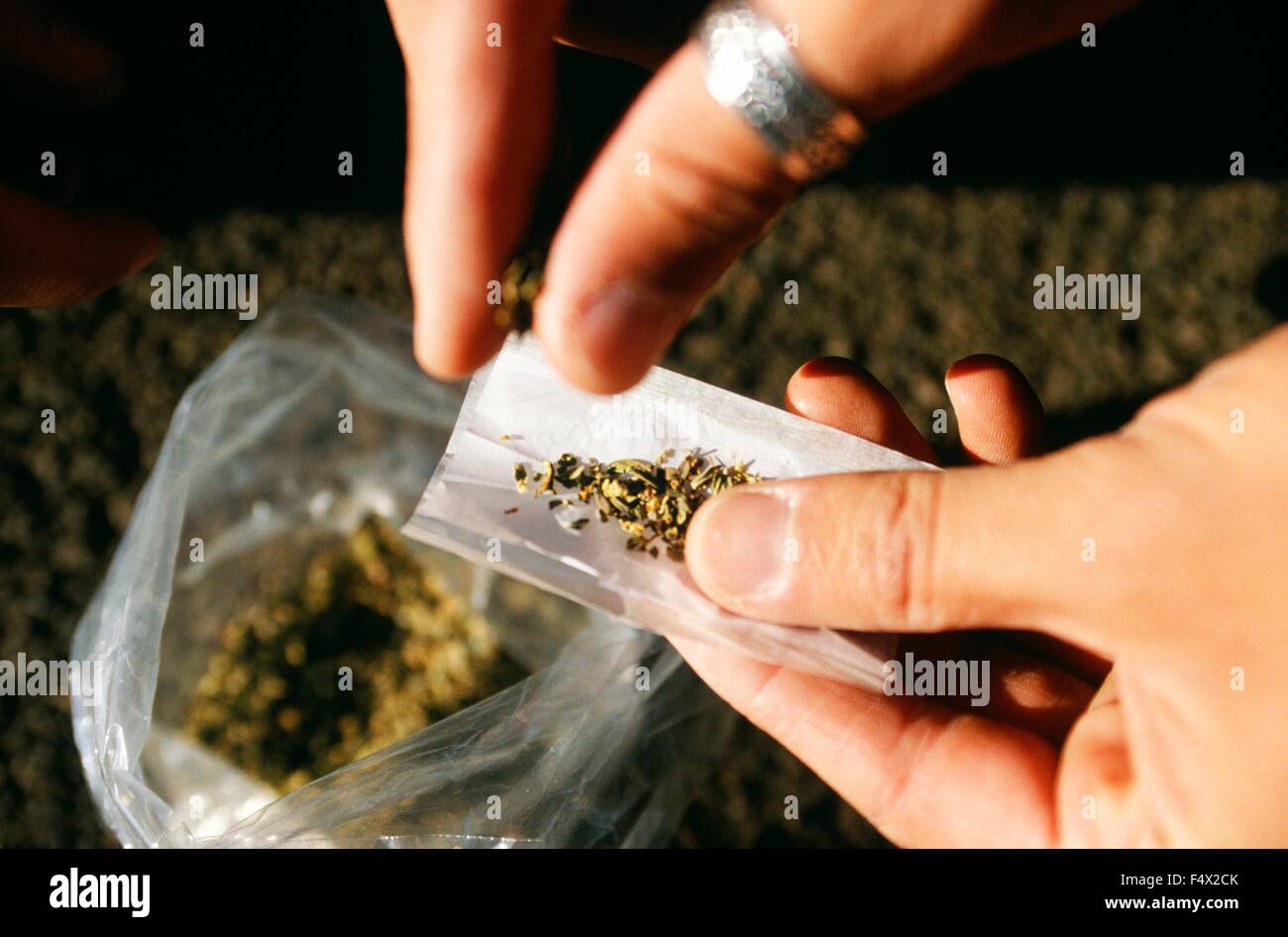 An addict rolls a joint using a synthetic cannabinoid called Spice use to spray on marijuana in order to enhance its psychoactive affect October 22, 2015 in Arlington, Virginia. Stock Photo