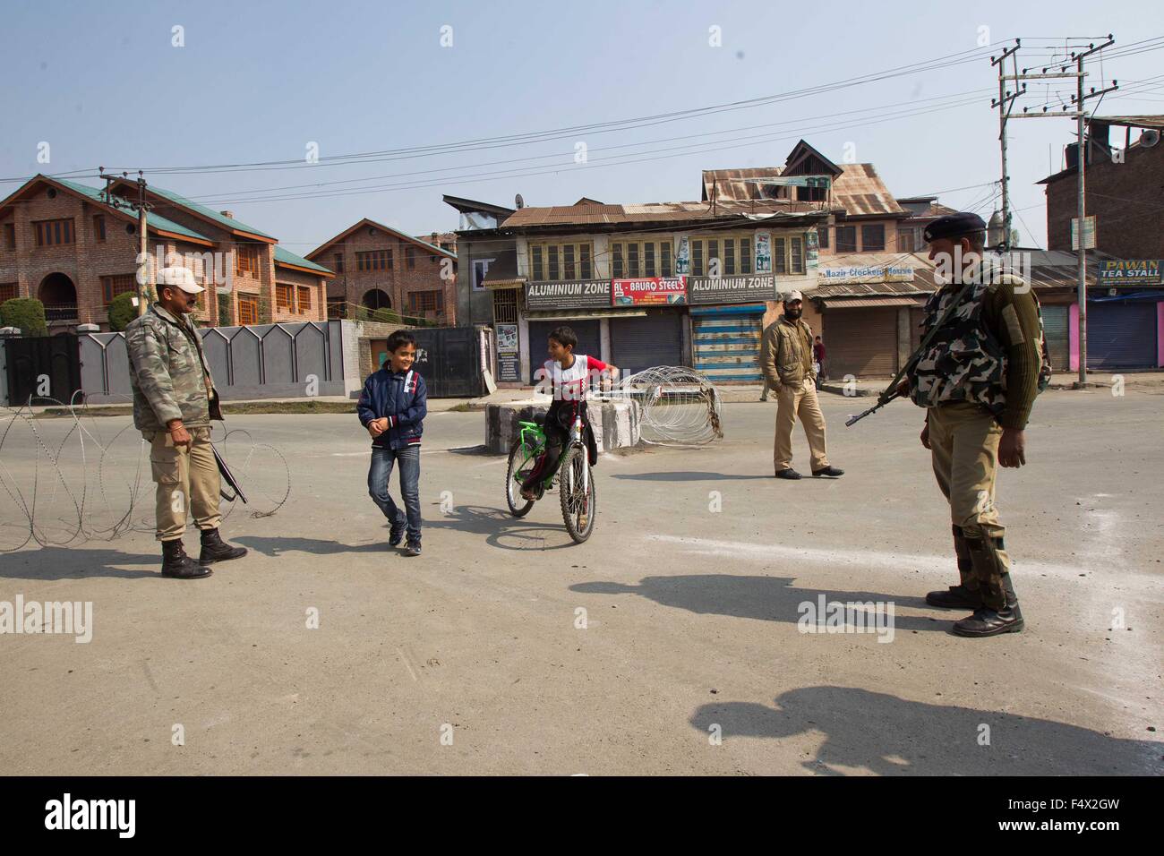 Srinagar, Indian-controlled Kashmir. 23rd Oct, 2015. Kashmiri boys play as Indian paramilitary soldiers stand guard during restrictions in old city of Srinagar, summer capital of Indian-controlled Kashmir, Oct. 23, 2015. The authorities on Friday imposed strict restrictions in several areas of restive Indian controlled Kashmir to disallow protest programme of separatist leaders and prevent clashes over killing of a trucker. Credit:  Javed Dar/Xinhua/Alamy Live News Stock Photo