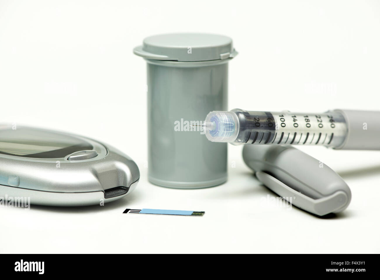 Insulin droplet on insulin pen needle with meter, strip and cannister. Stock Photo