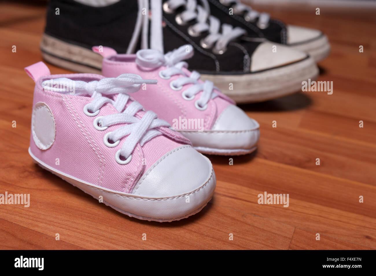 Cute pink baby girl sneakers and pair of adult sneakers Stock Photo