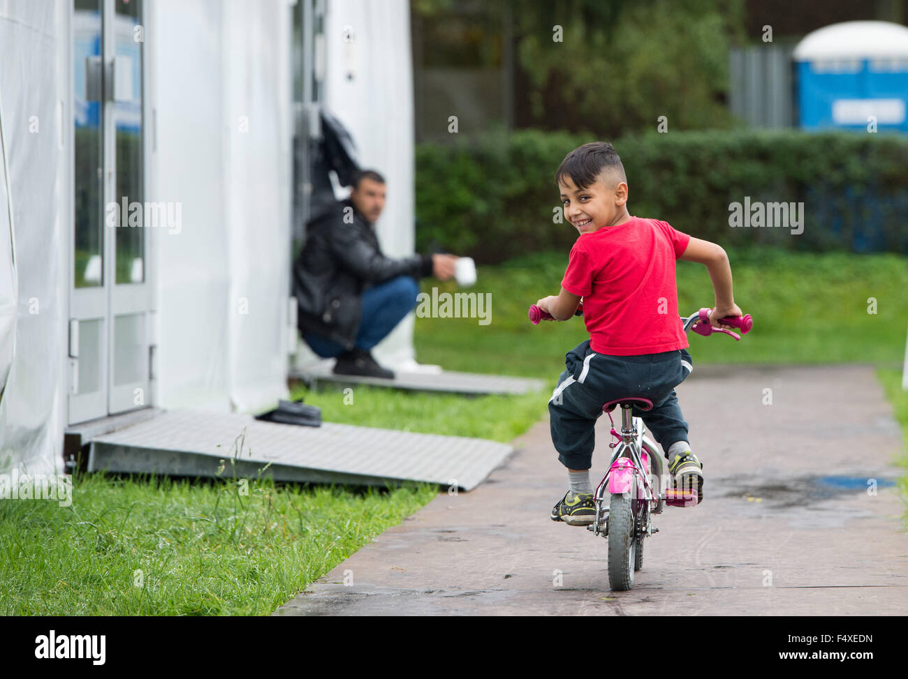 Duesseldorf, Germany. 22nd Oct, 2015. Seven-year-old refugee boy Sengin rides his bike in front of a refugee shelter in Duesseldorf, Germany, 22 October 2015. Photo: Monika Skolimowska/dpa/Alamy Live News Stock Photo