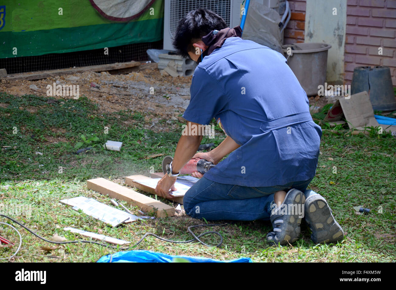 Man use cutting machine cut quarry tile at garden August 29, 2015 in