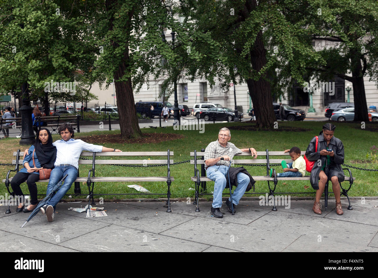 people of several races sit on bench in downtown manhattan new york city near city hall and brooklyn bridge Stock Photo