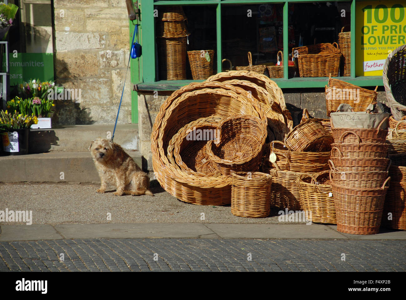 Wicker baskets ouside the shop and little dog in traditional rural Burford High Street, Cotswolds, Oxfordshire, England Stock Photo