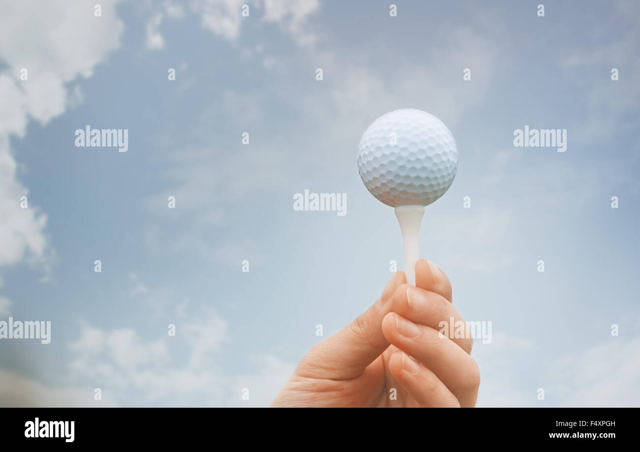 Human hand holding golf ball against the sky background Stock Photo