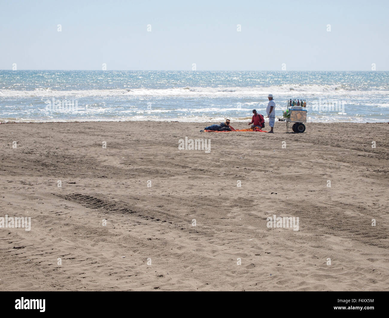 Two hawkers with a vendor's tray are offering their goods to tourists lying on the deserted beach of Lido di Ostia (Rome, Italy) Stock Photo
