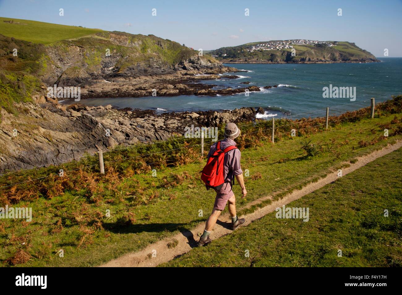 walking the Southwest Coast Path near Fowey in Cornwall, the village of Polruan visible in distance. Stock Photo