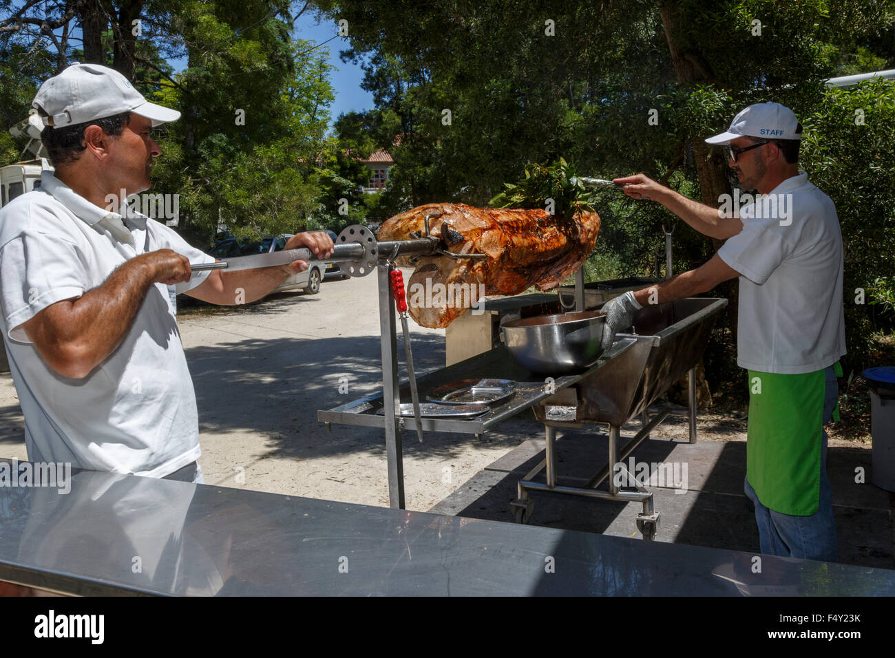 Two men attending to a large hog roast outdoors Portugal Stock Photo