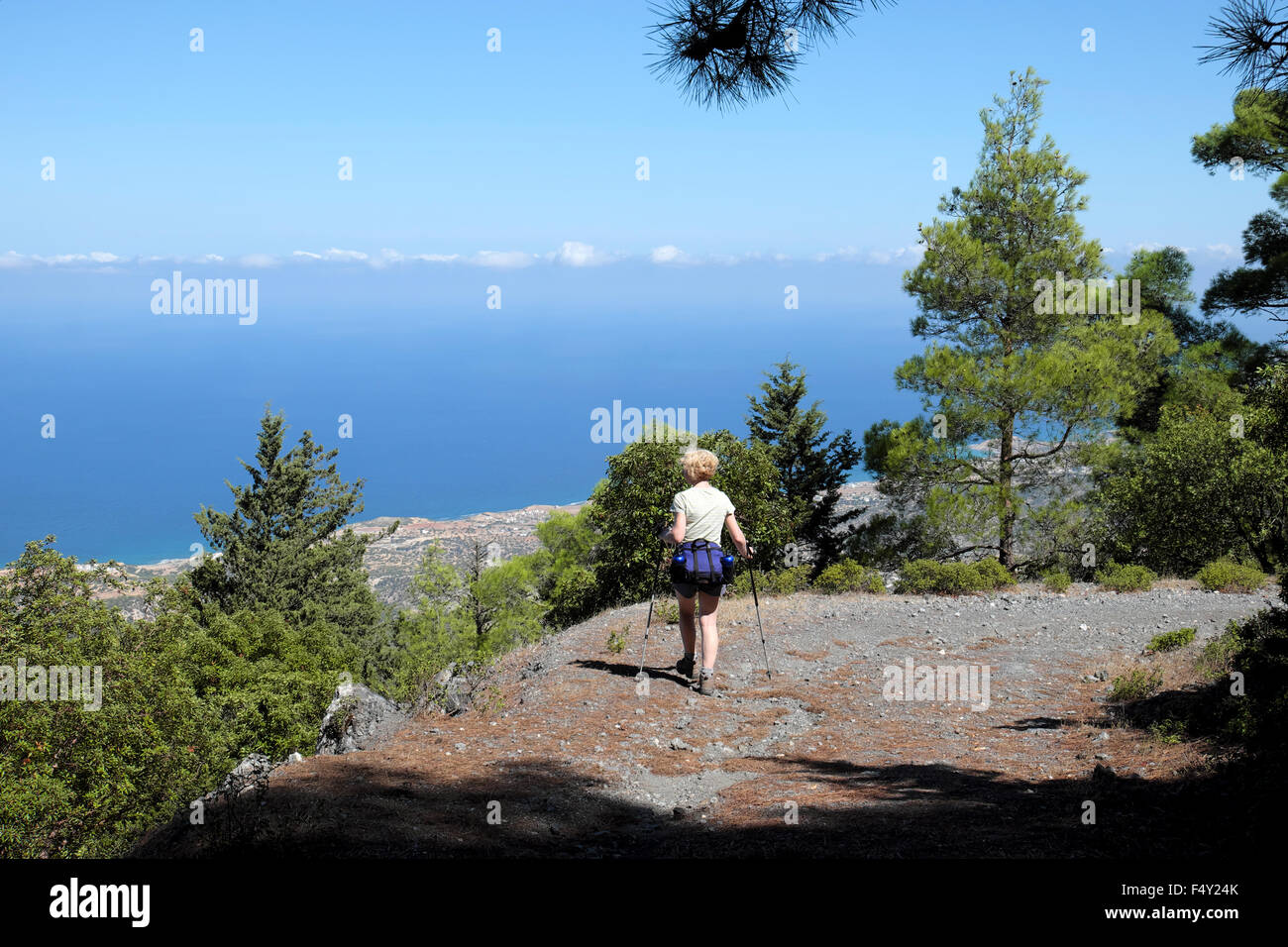 Back view of woman backpack & water bottles walking alone hiking on a September day looking out