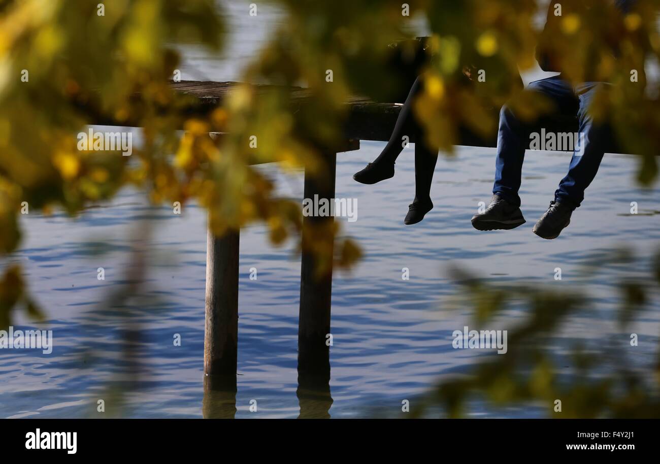 Stegen, Germany. 24th Oct, 2015. Excursionists dangle their legs off a dock on Lake Ammer near Stegen, Germany, 24 October 2015. Photo: KARL-JOSEF HILDENBRAND/dpa/Alamy Live News Stock Photo