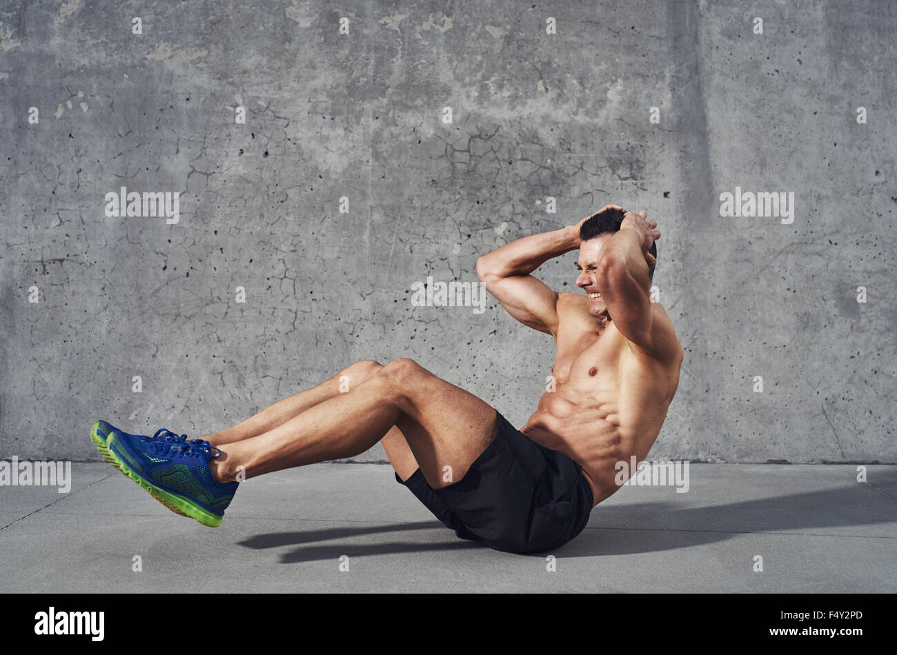 Fitness model exercising sit ups and crunches. Muscular well build, toned body with six pack sweating. Copy space Stock Photo