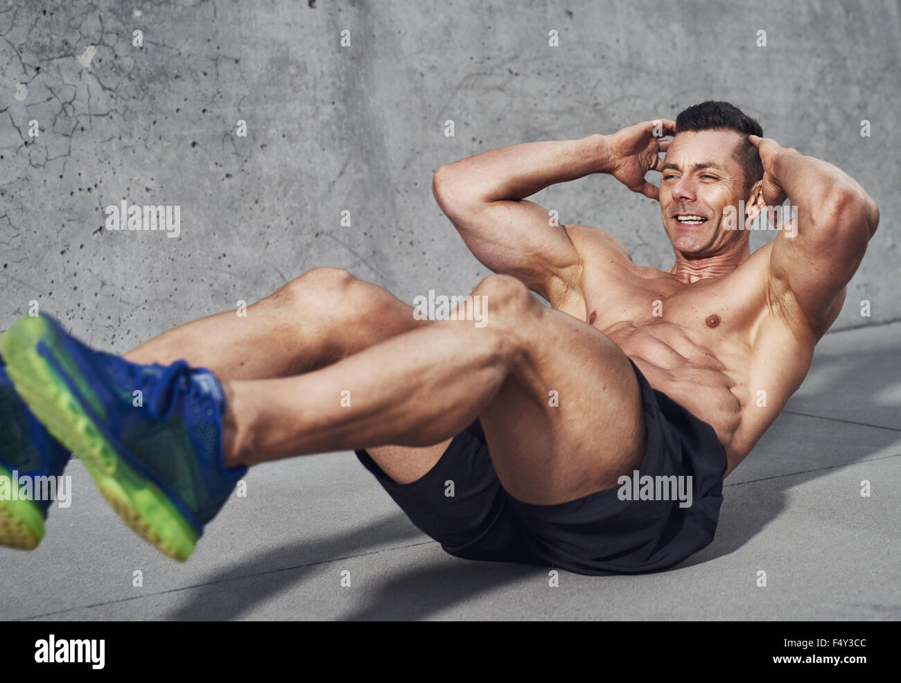 Muscular male fitness athlete doing sit ups, Clean look on grey