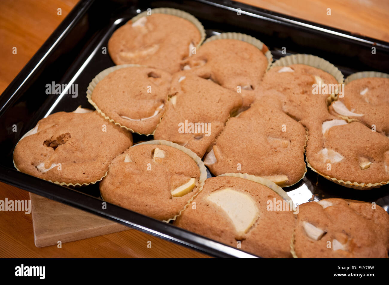 Failed flat muffins disaster, cupcakes in paper pan liners lying on black baking  tray on table, many sweet treats with apples Stock Photo - Alamy